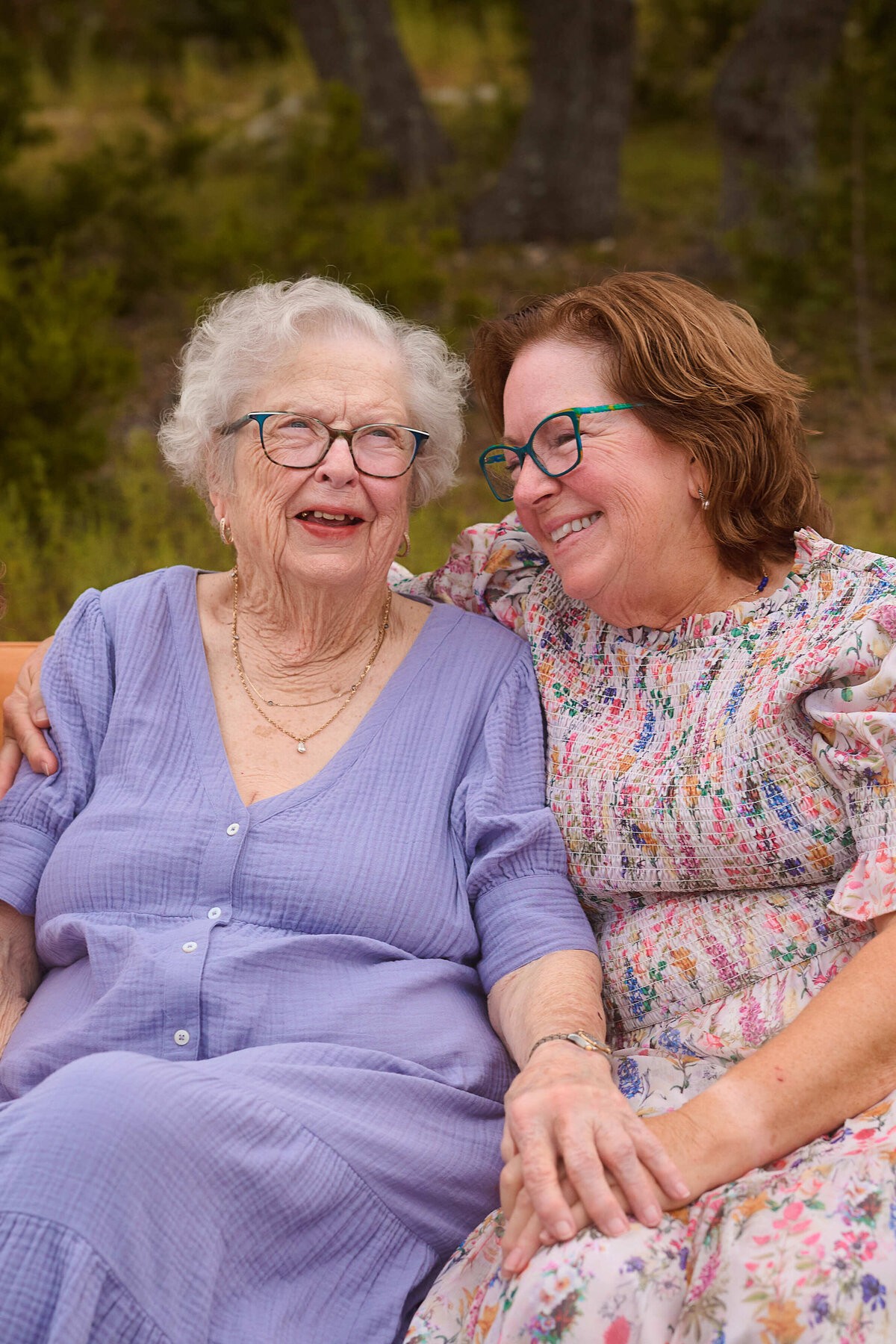 A grandmother and daughter sitting close together outdoors